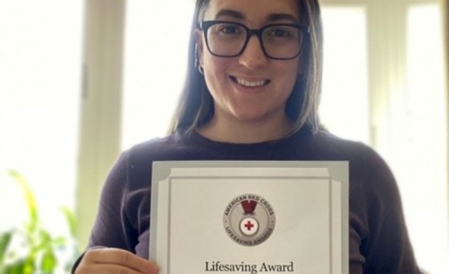 Image of a smiling woman holding up a Red Cross Lifesaving Award.