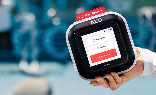 Avive Connect AED front with pull to start tab and your device, settings, and emergency buttons at gym.