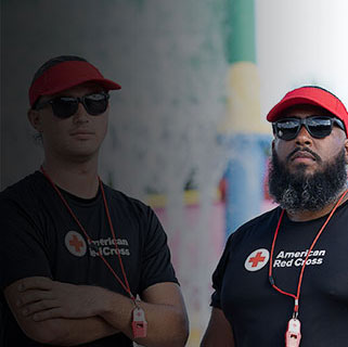 Two Red Cross lifeguards with visors at aquatic facility.