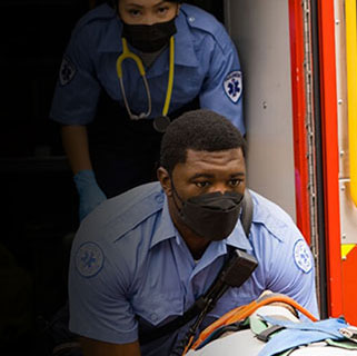 First responders transporting a patient on a wheeled stretcher.