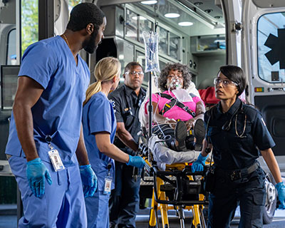 Emergency responders preparing a patient with an oxygen mask for ambulance transport, coordinating urgent care at the back of the vehicle during a critical medical situation.