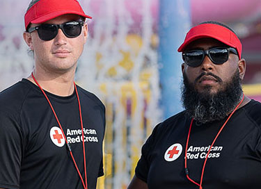Red Cross lifeguards with visors at aquatic facility.