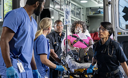 Emergency responders preparing a patient with an oxygen mask for ambulance transport, coordinating urgent care at the back of the vehicle during a critical medical situation.