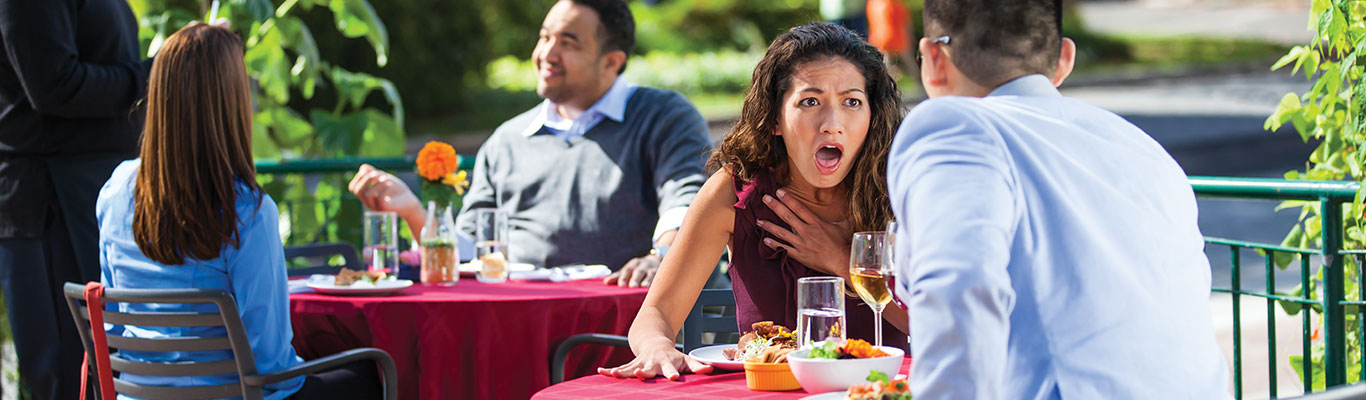 A woman experiencing difficulty breathing following an allergic reaction to food at a restaurant.