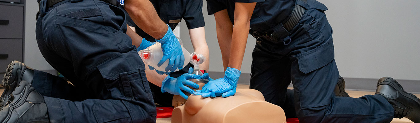 Healthcare professionals performing BLS training on a CPR manikin, practicing chest compressions and ventilation.