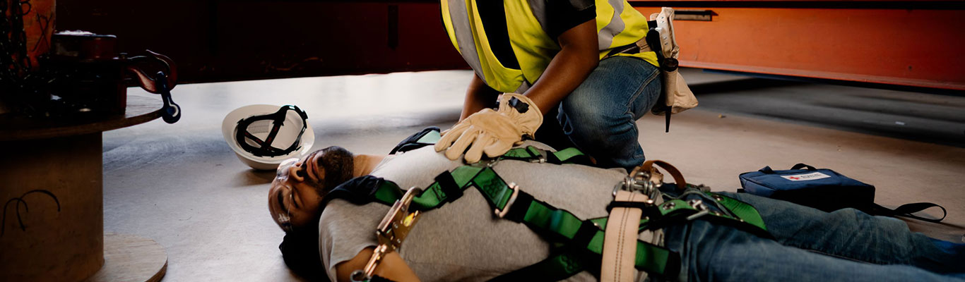 A worker checks for responsiveness on another worker who is unconscious.