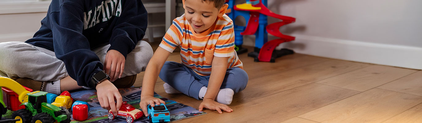 Babysitter playing with toy cars with a young child.