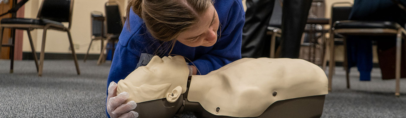 Woman practices hands-only CPR during a CPR and First Aid Red Cross training.