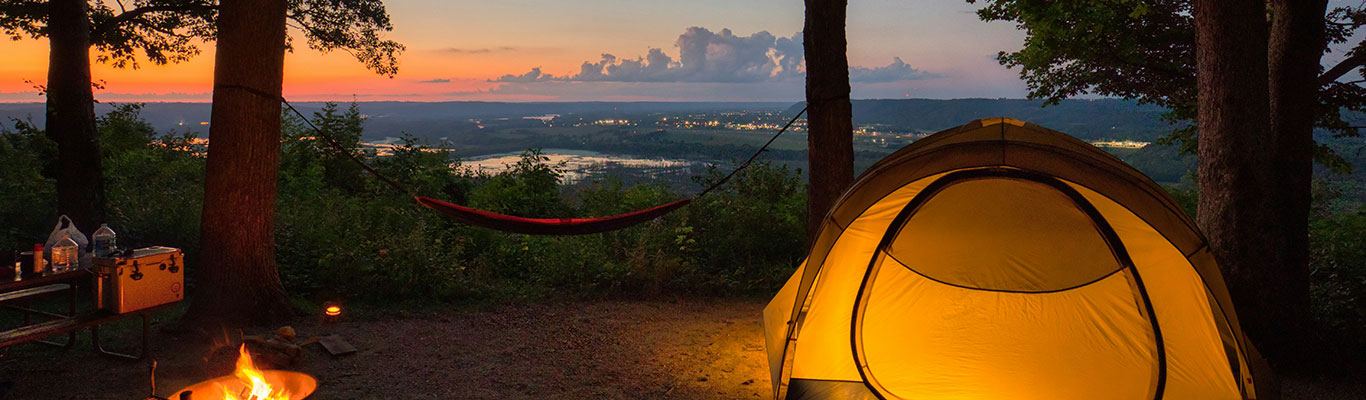 Wilderness campsite with tent, campfire, and camping supplies.