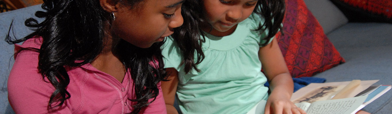 Babysitter reading to child on the couch.