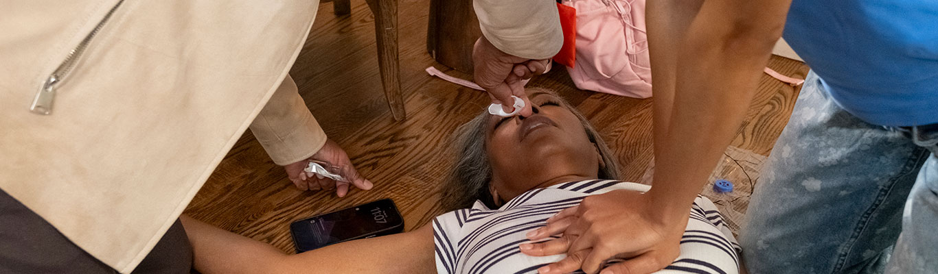 People administering naloxone nasal spray and performing CPR on someone experiencing an opioid overdose emergency.