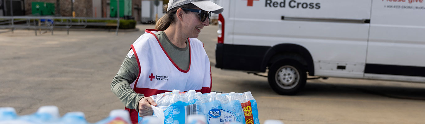 Red Cross volunteer distributing bottled water to help a community impacted by natural disaster.