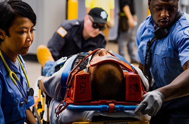 Paramedics bringing an injured person into an ambulance on a stretcher.