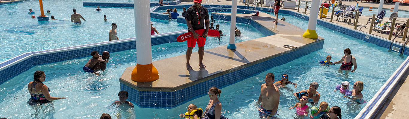 Lifeguard overseeing families swimming in a public pool.