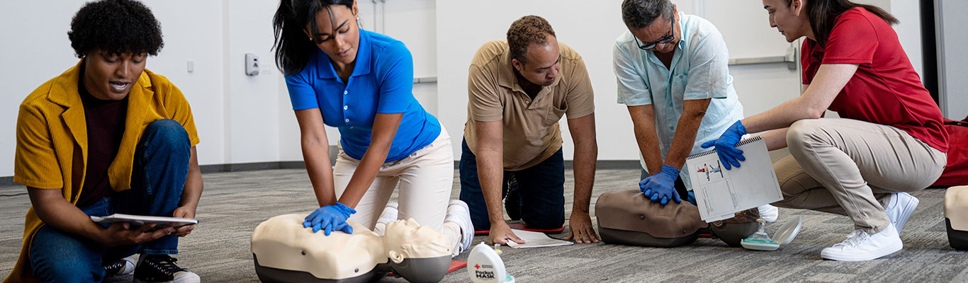 Group of adults practicing CPR on CPR manikins during an American Red Cross CPR certification class.