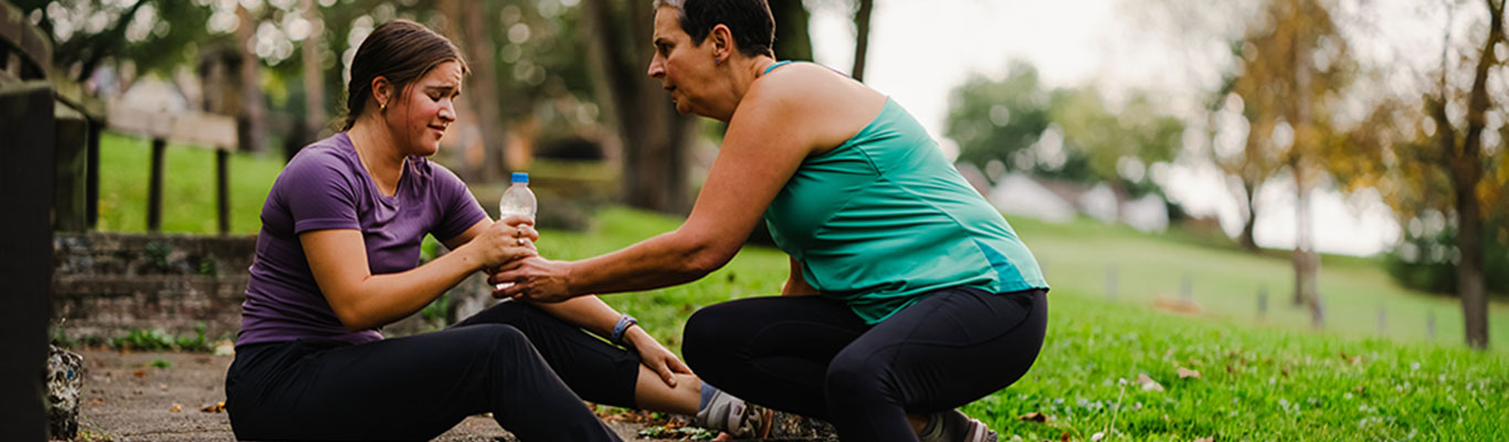 'Bystander performing lifesaving skills on injured woman in park.