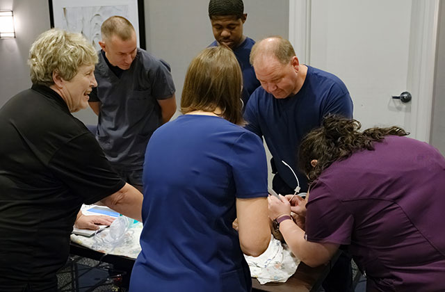 Healthcare professionals participating in Neonatal Advanced Life Support (NALS) training session with medical equipment.