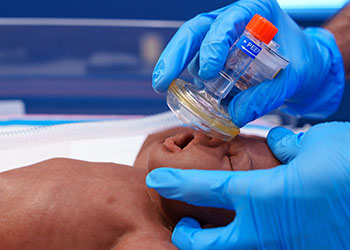 Medical professional applying neonatal resuscitation techniques.