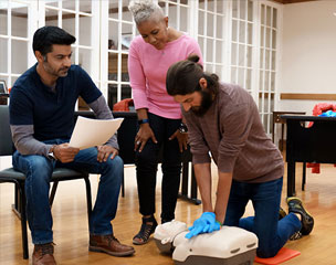 A man practices performing CPR in Spokane, Washington while other students watch and the instructor monitors.