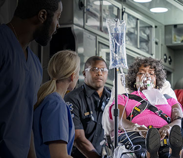 First responders helping a patient into an ambulance.