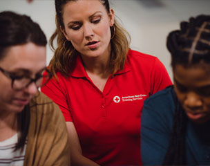 Red Cross instructor observing two trainees.