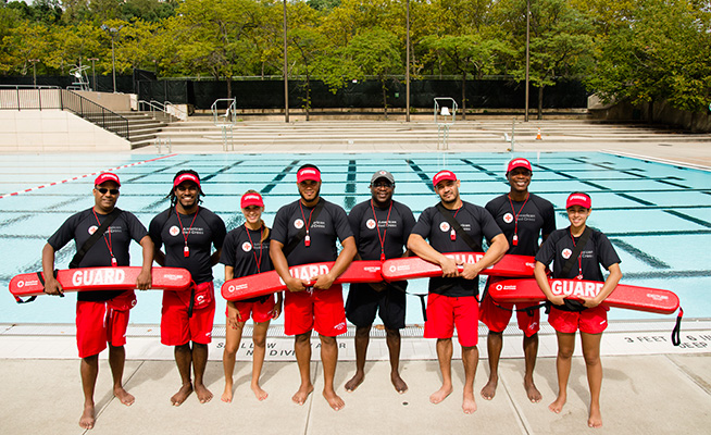 Group of certified Red Cross lifeguards standing near a pool.