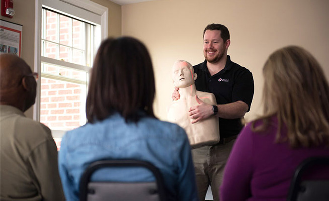 CPR Instructor with manikin leading a CPR training course.