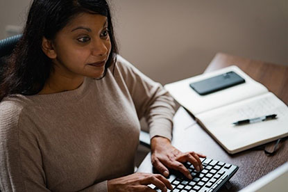 Woman at a computer typing on a keyboard.