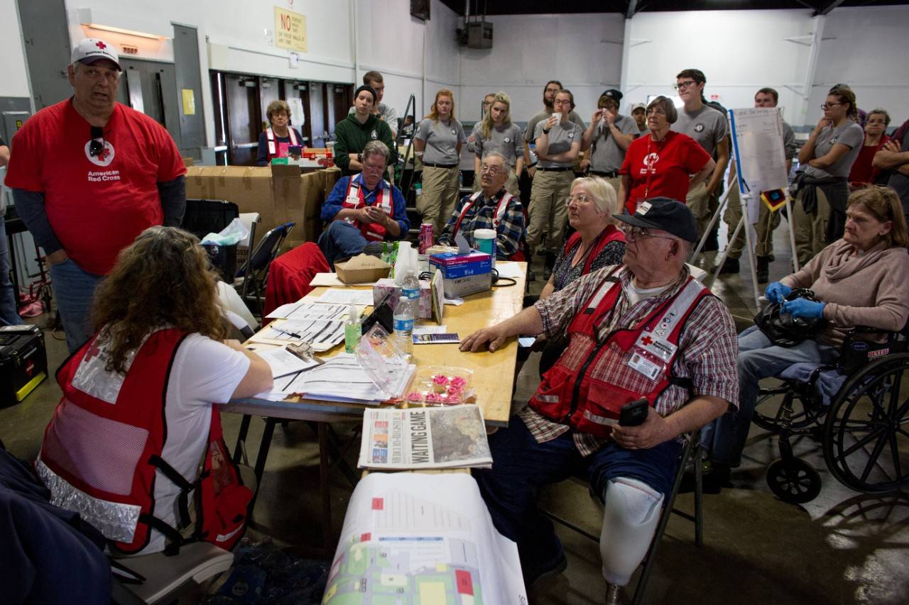 February 14, 2017. Chico, California.
Red Cross workers congregate for an afternoon meeting in the Silver Dollar Fairgrounds shelter in Chico, CA. Shelter manager Daryl White (far left) lead the meeting and discussed contingency plans if the Oroville Dam conditions worsen.
Photo by Marko Kokic for the American Red Cross, Oroville Evacuations to Red Cross Shelters
