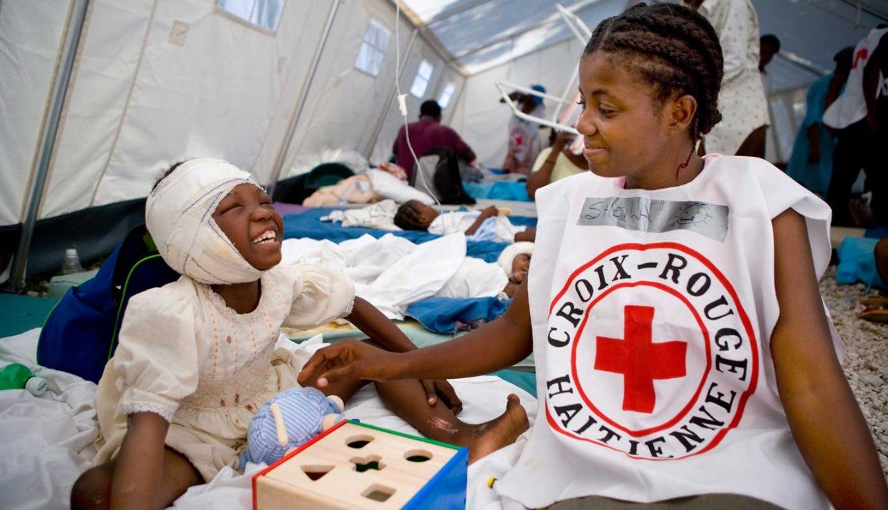 Volunteer plays with injured girl in temporary hospital