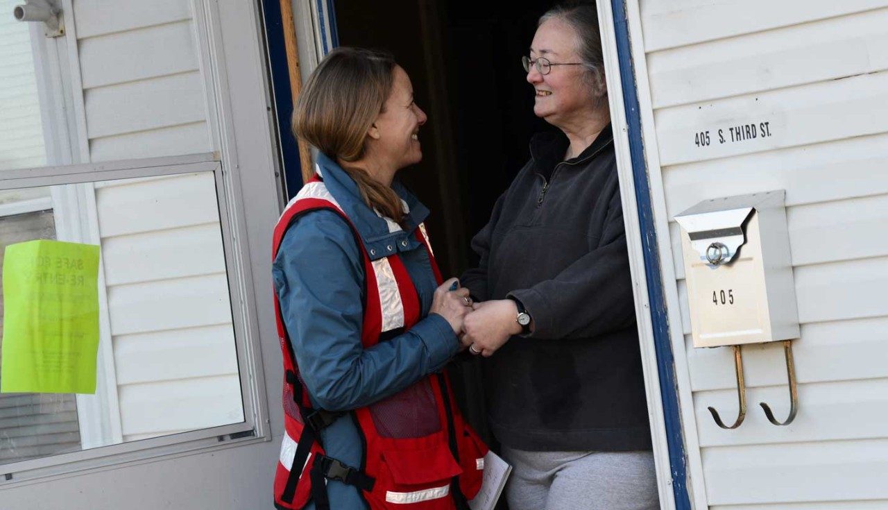 Female Red Cross volunteer speaking with woman outsider her home