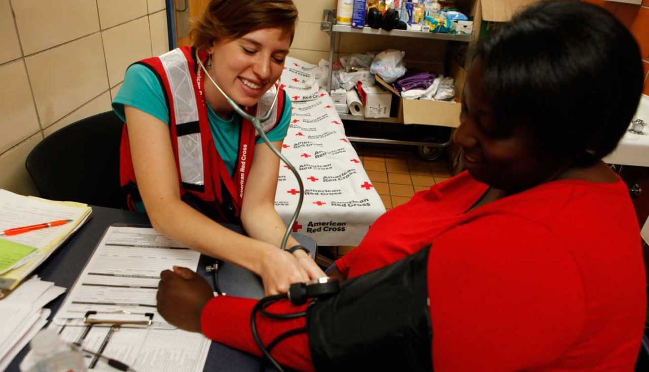 Red Cross volunteer checking another person's blood pressure