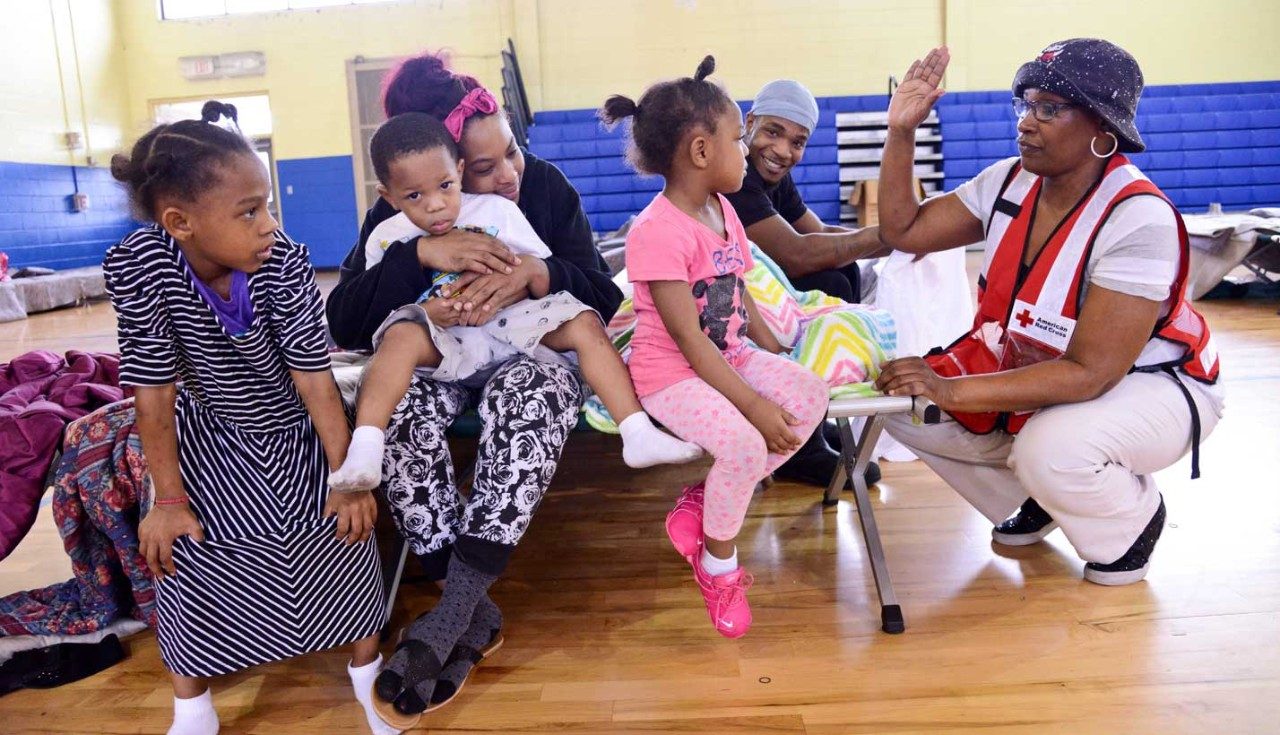 Red Cross volunteer talking with family in shelter