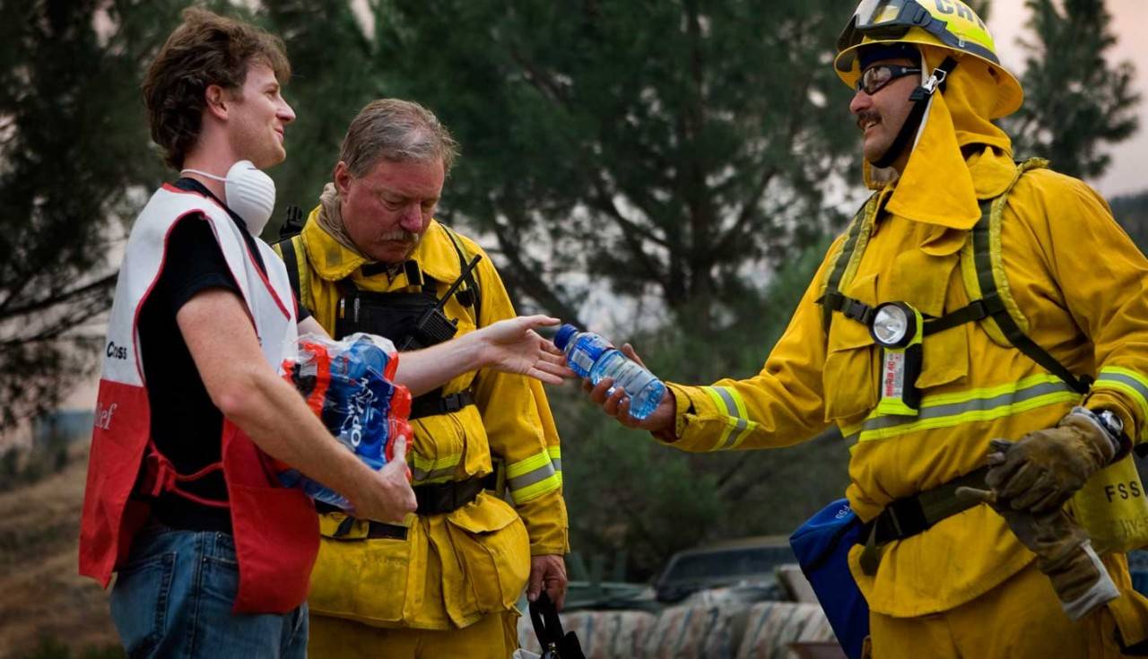 Volunteer giving water to a firefighter