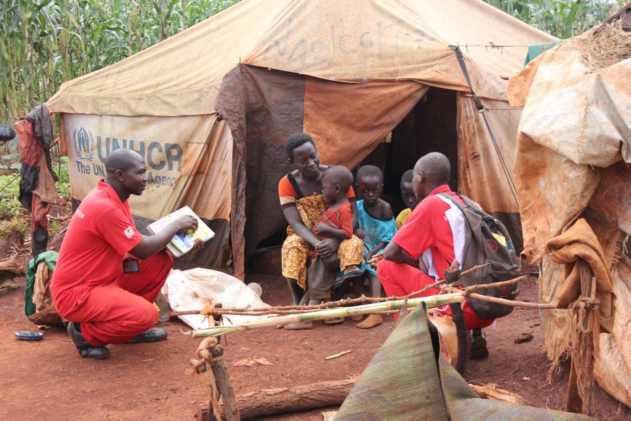 Nyarugusu Refugee Camp, Tanzania Feb 2016

Ntwengeye Fabien, 35, and Nduwayo Elie, 32, both members of the Tanzania Red Cross Health Information Team (HIT), go door-to-door in the Nyarugusu refugee camp to spread the word about relevant health issues. HIT is a group of nearly 170 Burundian refugees that use music, dance and door-to-door social mobilization to share critical health information in the Nyarugusu refugee camp in Western Tanzania. Here, they visit Kabura Dorotea, 30, to talk about malaria, describing the symptoms and what to do if she suspects someone in her family has it. The group tackles a range of health issues, including malaria and cholera prevention, hygiene promotion, and the availability of health care services to pregnant mothers, working tirelessly to get the word out. Since May 2015, pre-electoral violence in Burundi led to an increasing number of refugees entering the camp, putting an overwhelming amount of pressure on already limited resources. Tanzania Red Cross runs health facilities in both Nyarugusu and Mtendeli, a camp three hours to the north. , Overwhelming Need for Ambulance in Tanzania Refugee Camp