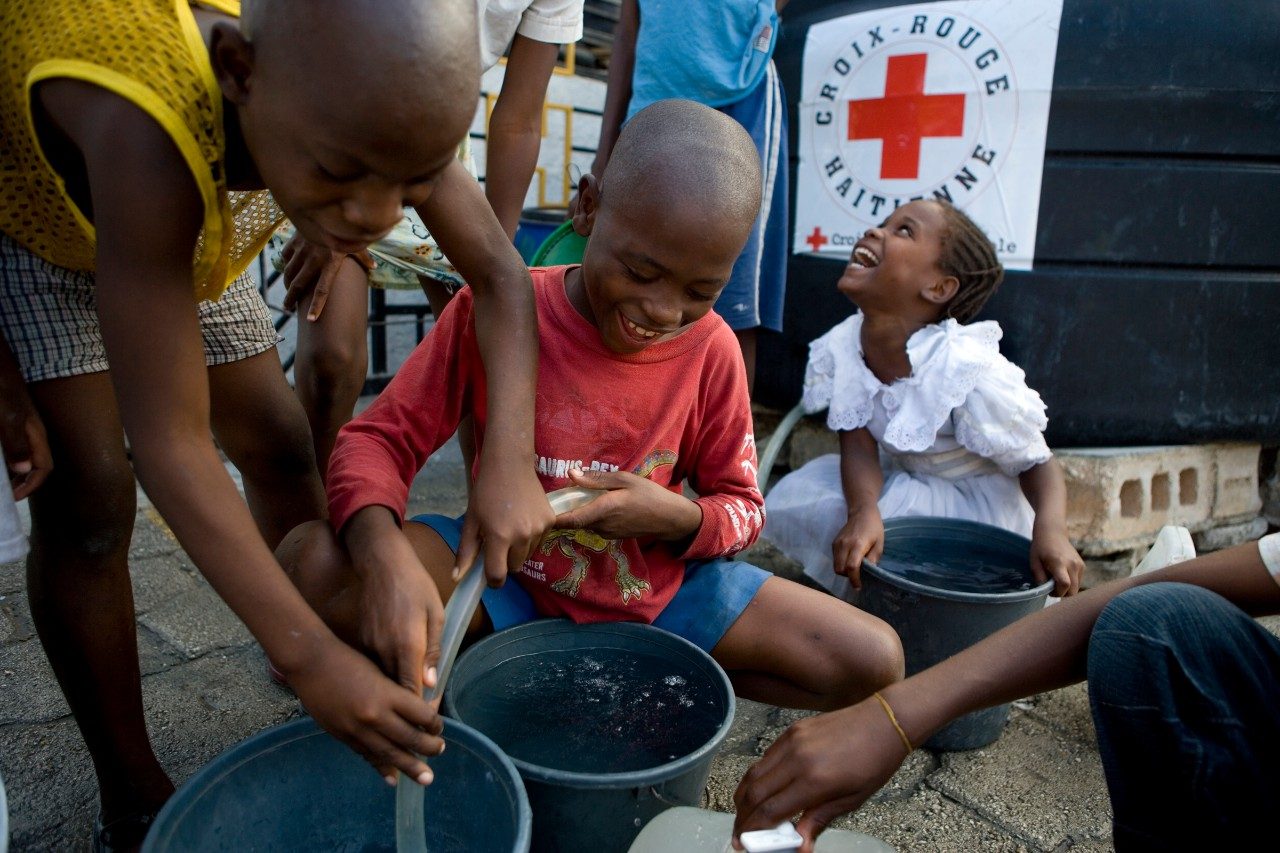 group of happy children pouring water hose in bucket