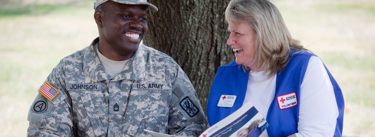 Red Cross volunteer providing information to a military personnel