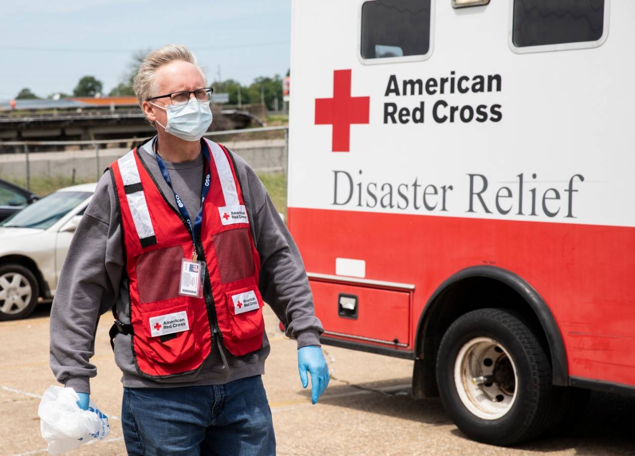 April 18, 2020.  Monroe, Louisiana.
Charles "Harry" Murphy, Jr., BS, NRP the Emergency Management Coordinator for the Louisiana Region, Cap/West Chapter, carries a container full of masks and hand sanitizer into a hotel where individuals and families affected by a recent tornado are staying in Monroe, LA, on Saturday, April 18, 2020. Hundreds of residents needed shelter after the storm. Normally the Red Cross would set up shelters, but due to the pandemic and social distancing guidelines, people who were unable to stay in their homes have been given rooms in various local hotels.
Photo by Scott Dalton/American Red Cross