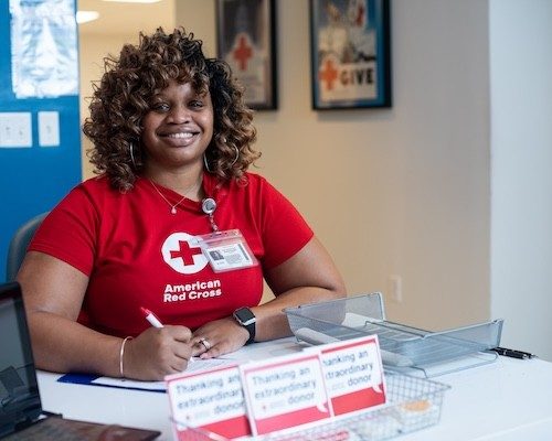 A Red Cross blood donor ambassador sitting at a signup table