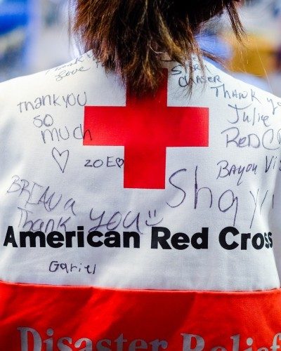 red cross volunteer wearing a disaster vest covered with signatures and hand written thank you messages.