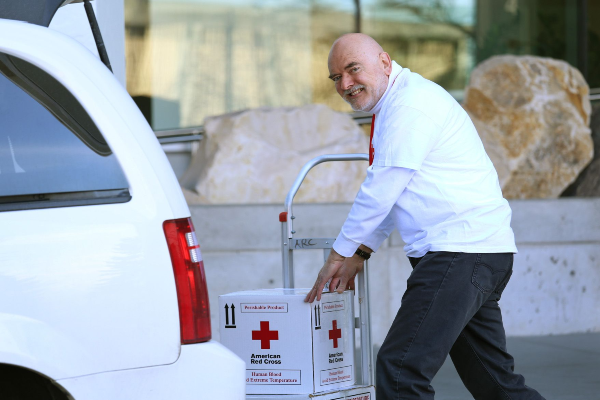 smiling male volunteer loads blood products into transportation vehicle
