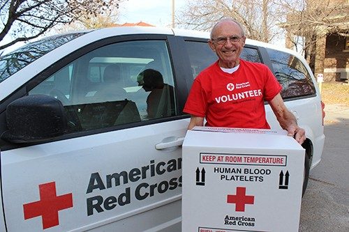 A Red Cross Volunteer carying a box.