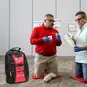 Red Cross First Aid Instructor showing a student how to use a Tourniquet Arm Trainer, and a Red Cross Instructor bag.