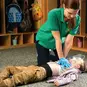 A woman performing compressions on a child wearing a CPR face shield.