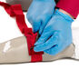 Trainee wrapping bleeding control tourniquet on arm trainer.