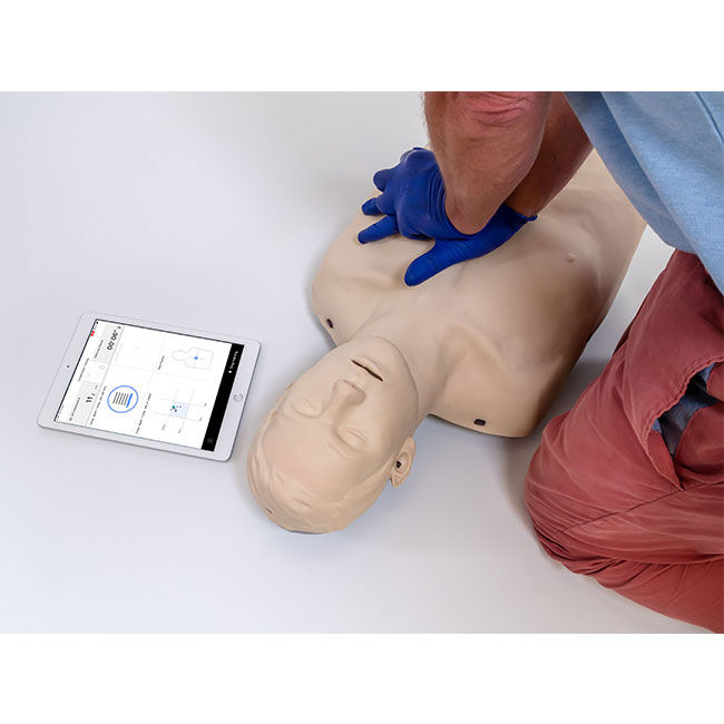 Student practicing CPR compressions on a Brayden CPR Pro Adult Manikin  next to an iPad with CPR metrics.