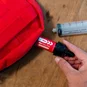 Sawyer Mini Water Filter connected to a red hydration pack, using the syringe plunger to extract and filter water.