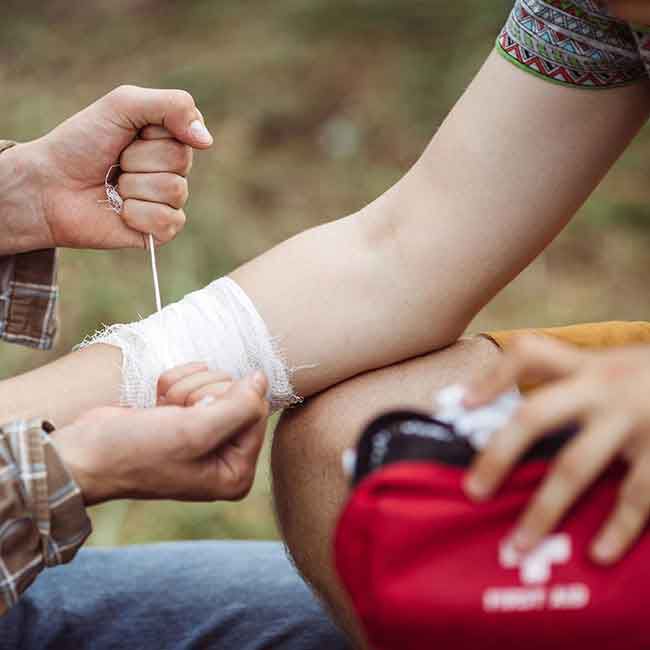 An injured person getting their arm bandaged by a responder.