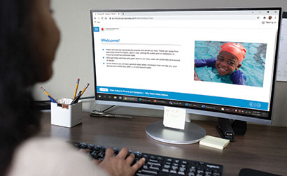 A person using a computer to access online water safety content from the American Red Cross.
