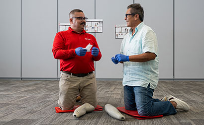 Red Cross Instructor showing a student how apply a tourniquet with tourniquet arm trainers.